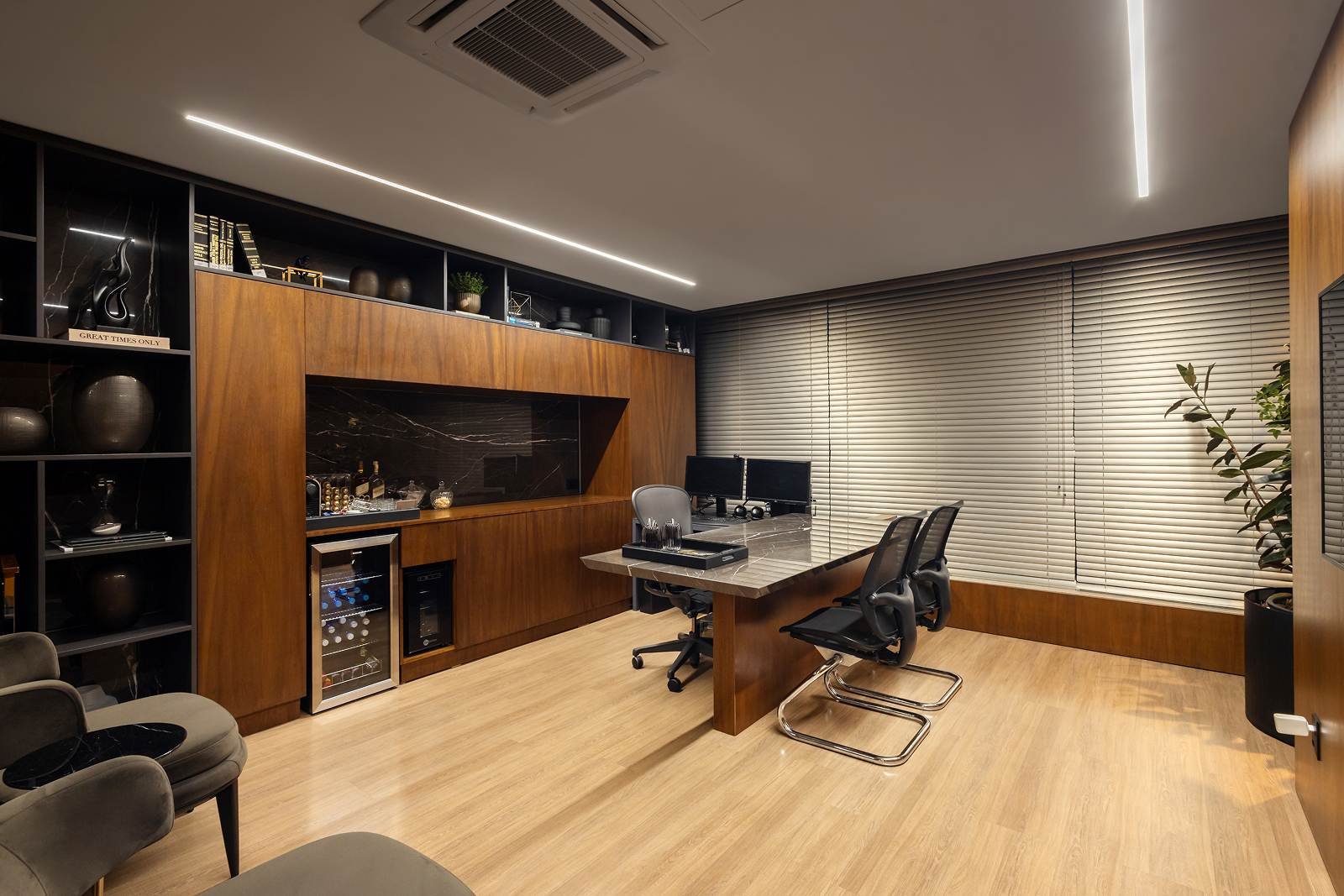 Sala de atendimento com mesa de trabalho, poltronas e adega